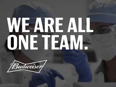 A Budweiser campaign showing two health workers and the text "We are all one team"