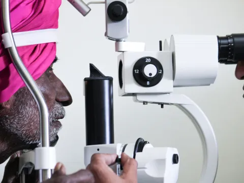 A doctor checks an older man's eyes for cataracts at the Julia Hospital Jamkhed India