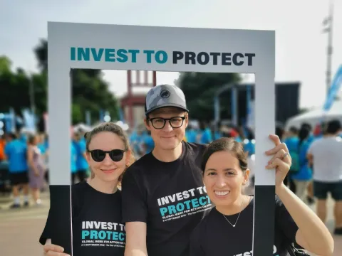People holding up Invest to Protect on NCDs placard at a fun run in Geneva