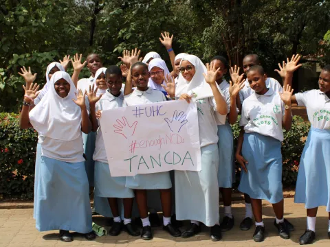 Tanzanian children holding up universal health coverage sign