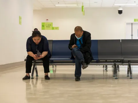 Two people look at their smartphones in a hospital waiting room in China