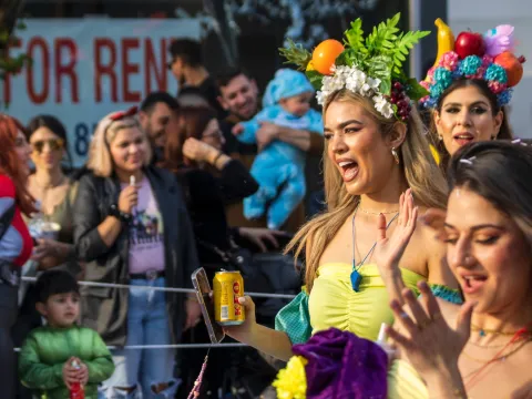 Women holding a beer with children in the background in a carnival parade in Chipre