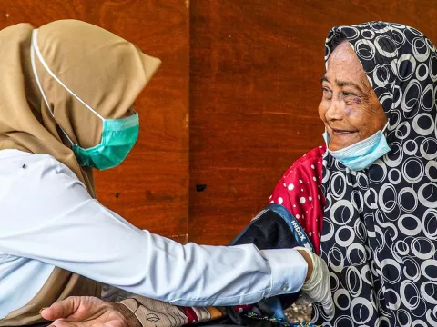 health worker in indonesia taking blood pressure