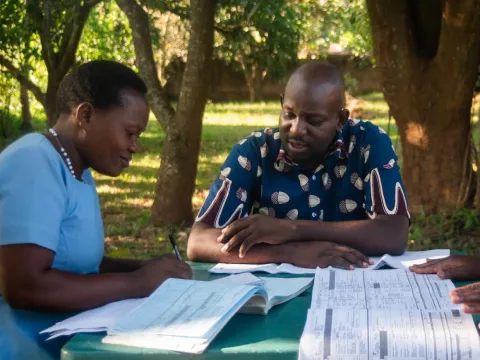 3 people looking over health data outside in Malawi