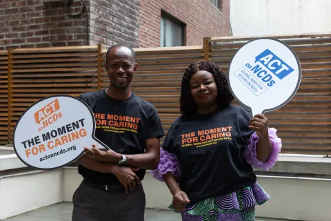 Two people african decent holding up 'act on ncds' signs