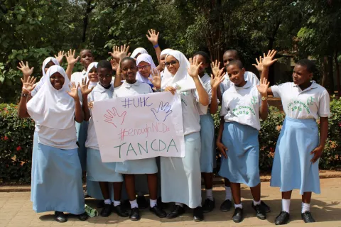 Tanzanian children holding up universal health coverage sign