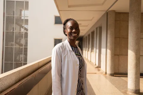 Woman doctor in Kenya smiling at the camera in outside hallway of hospital