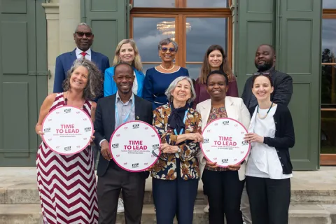 ncd advocates at a meeting in geneva smiling and holding time to lead campaign signs