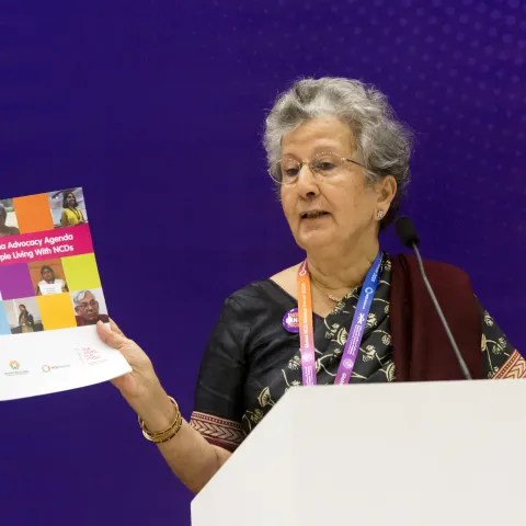 Woman holding NCD advocacy booklet at a conference