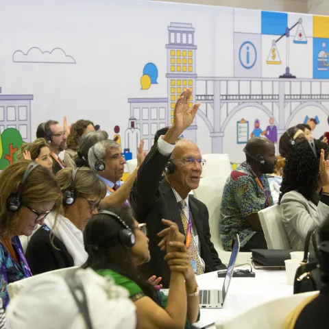 Man raising his hand at an NCD Alliance conference on NCDs