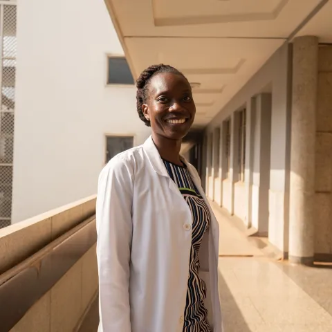 Woman doctor in Kenya smiling at the camera in outside hallway of hospital