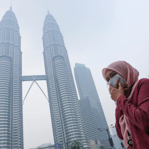 woman wearing mask covers her mouth to protect herself from air pollution in Kuala Lumpur