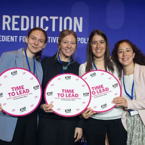 NCDA staff smiling and holding 'time to lead' sign at geneva salt reduction event
