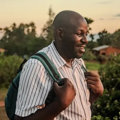 man smiling with backpack on walking in a field