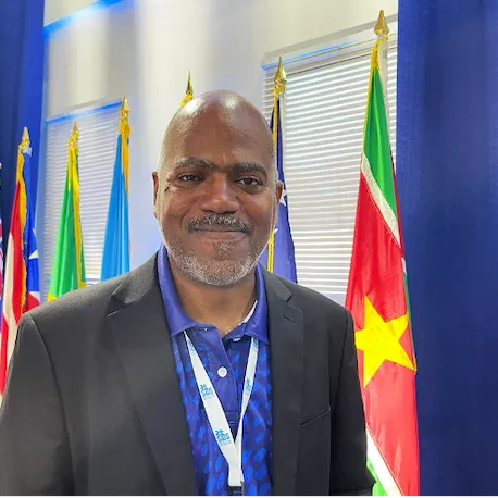 Man smiling in front of Caribbean country flags